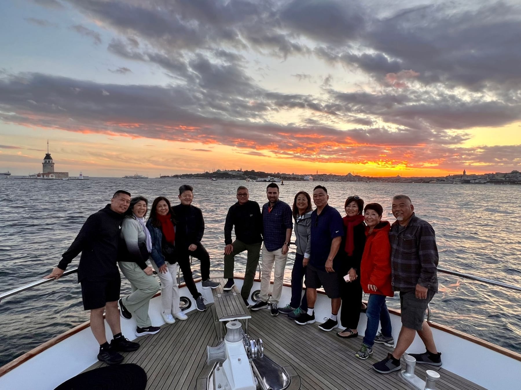 A happy private tour group together on a boat at golden sunset on the Bosphorus, with the Maiden's Tower and the Istanbul skyline behind them