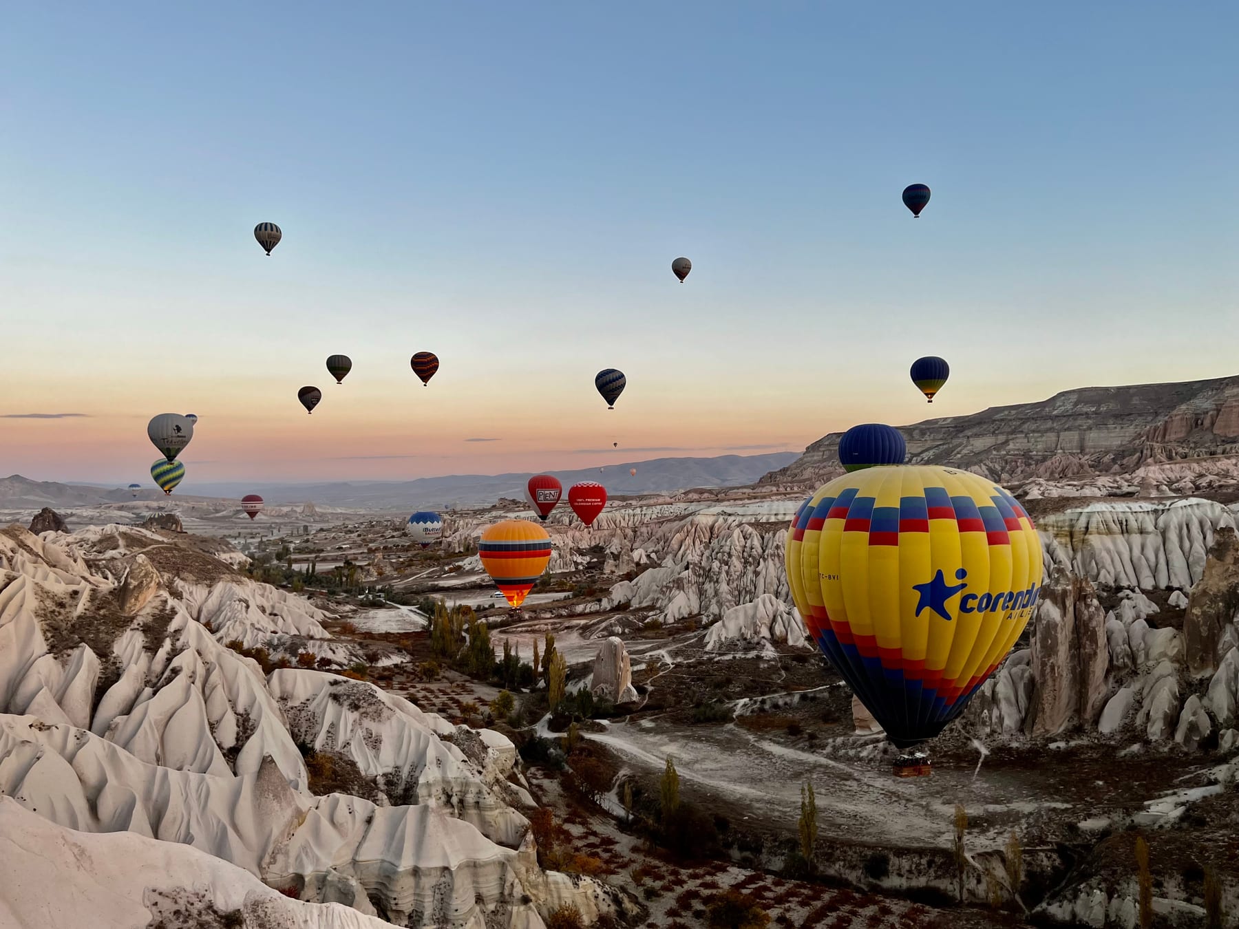 Colourful hot-air balloons drifting over the rose valleys and fairy chimneys of Cappadocia at sunrise